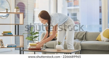 Woman, cleaning and house with books in lounge, table and organize for housekeeping, tidy and order. Happy cleaner girl, book stack and living room for clean home, neat apartment or flat in New York