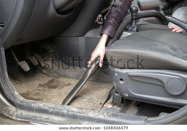 Woman\
cleaning interior of car with vacuum\
cleaner