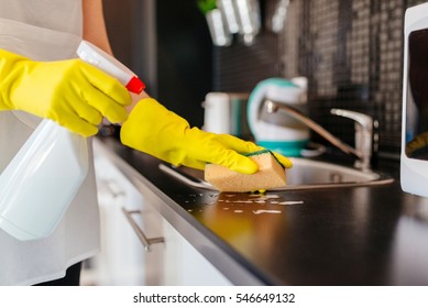 Woman cleaning kitchen cabinets with sponge and spray cleaner. - Powered by Shutterstock