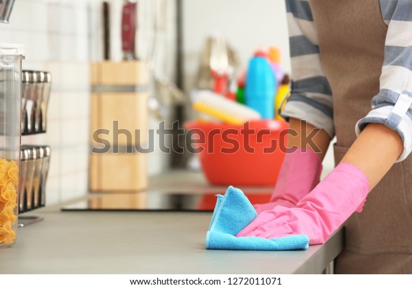 Woman cleaning\
kitchen counter with rag,\
closeup