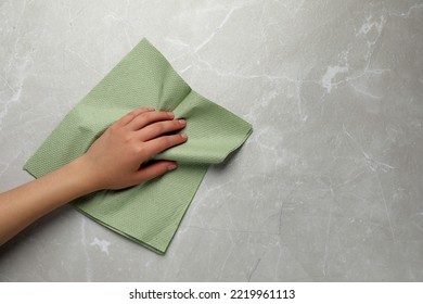 Woman Cleaning Light Grey Table With Paper Towel, Top View. Space For Text