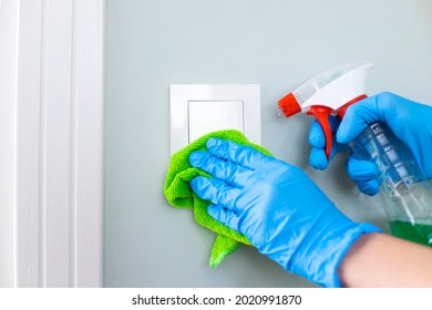 Woman Cleaning A Light Switch With A Disinfecting Spray