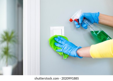 Woman Cleaning A Light Switch With A Disinfecting Spray