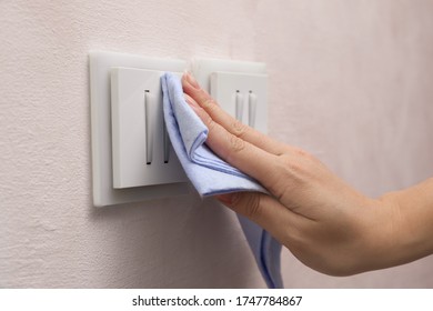 Woman Cleaning Light Switch With Rag Indoors, Closeup