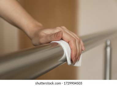 Woman Cleaning Metal Railing With Antiseptic Wipe Indoors, Closeup