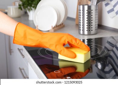 Woman Cleaning Oven Cooktop With Sponge In Kitchen, Closeup