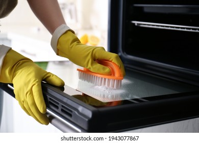 Woman Cleaning Oven Door With Baking Soda In Kitchen, Closeup