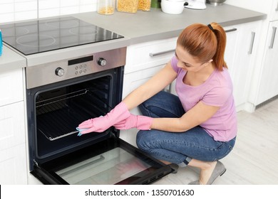 Woman Cleaning Oven Rack With Rag In Kitchen