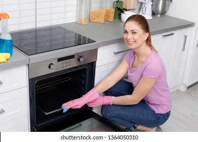 Woman Cleaning Oven Rack With Rag In Kitchen