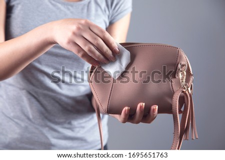 woman cleaning pink bag on grey background