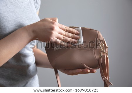 woman cleaning pink bag on grey background