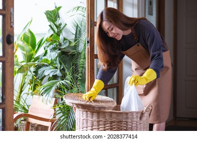 A Woman Cleaning And Putting Garbage Into The Trash Bin At Home