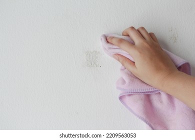 Woman Cleaning And Remove Sticky Rough Glue And Tape Remain On The Old Concrete Wall.