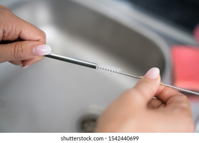 Woman Cleaning Reusable Metal Straw In Kitchen