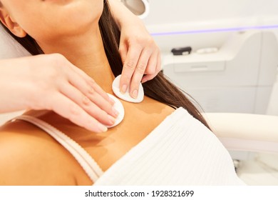 Woman cleaning skin with cotton pads on cleavage with beautician in the cosmetic studio