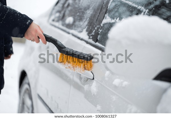 Woman cleaning snow from the car in the winter.\
Car handle.