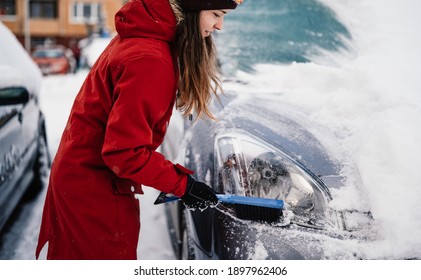 Woman Cleaning Snow Off His Car During Winter Snowfall. Scraping Ice. Winter Window Cleaning.