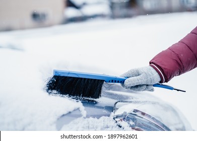 Woman Cleaning Snow Off His Car During Winter Snowfall. Scraping Ice. Winter Window Cleaning.