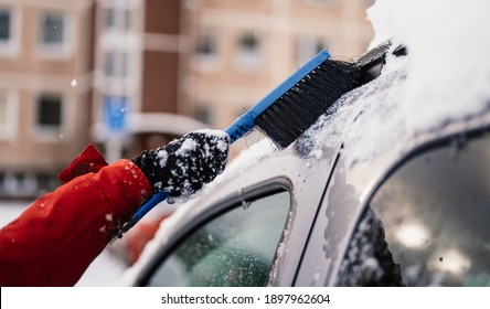 Woman Cleaning Snow Off His Car During Winter Snowfall. Scraping Ice. Winter Window Cleaning.