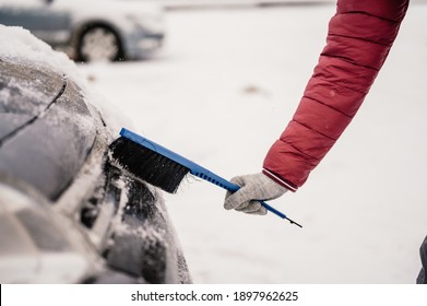 Woman Cleaning Snow Off His Car During Winter Snowfall. Scraping Ice. Winter Window Cleaning.