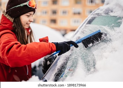 Woman Cleaning Snow Off His Car During Winter Snowfall. Scraping Ice. Winter Window Cleaning.