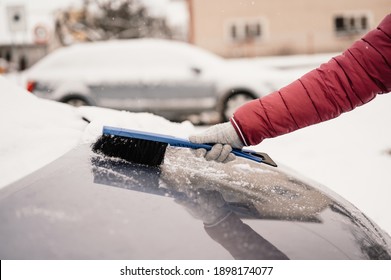 Woman Cleaning Snow Off His Car During Winter Snowfall. Scraping Ice. Winter Window Cleaning.