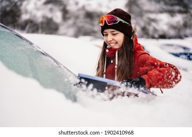 Woman Cleaning Snow Off His Car During Winter Snowfall. Scraping Ice. Winter Window Cleaning.