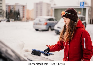 Woman Cleaning Snow Off His Car During Winter Snowfall. Scraping Ice. Winter Window Cleaning.