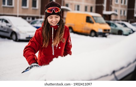 Woman Cleaning Snow Off His Car During Winter Snowfall. Scraping Ice. Winter Window Cleaning.