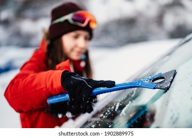 Woman Cleaning Snow Off His Car During Winter Snowfall. Scraping Ice. Winter Window Cleaning.