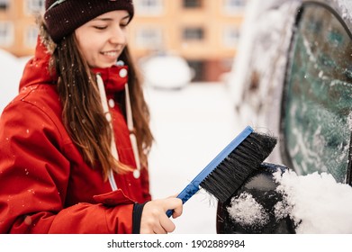 Woman Cleaning Snow Off His Car During Winter Snowfall. Scraping Ice. Winter Window Cleaning.