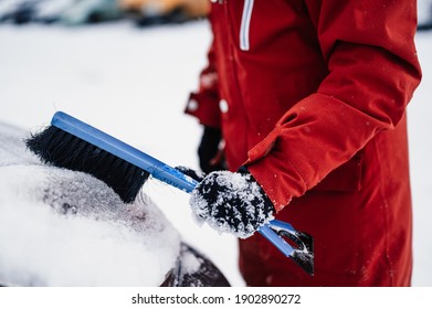 Woman Cleaning Snow Off His Car During Winter Snowfall. Scraping Ice. Winter Window Cleaning.