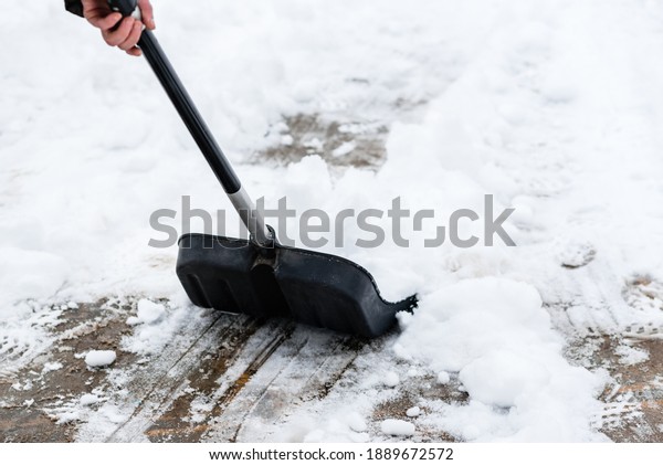 Woman\
cleaning snow from sidewalk and using snow\
shovel.