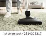 Woman cleaning soft carpet with vacuum cleaner at home, closeup