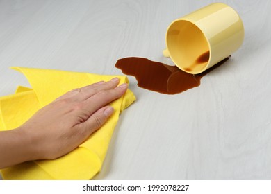 Woman Cleaning Spilled Coffee On White Wooden Table, Closeup