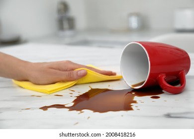 Woman Cleaning Spilled Coffee On White Marble Table In Kitchen, Closeup