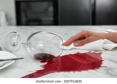 Woman Cleaning Spilled Wine On White Marble Table In Kitchen, Closeup