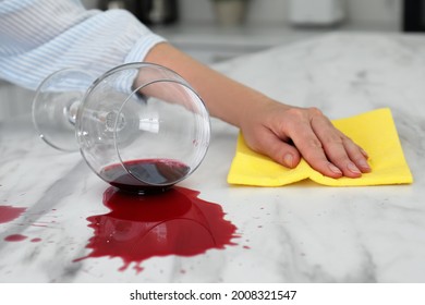 Woman Cleaning Spilled Wine On White Marble Table Indoors, Closeup