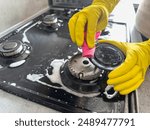 woman cleaning  sponge rag with white foam and detergent washing kitchen gas stove. House cleaning concept