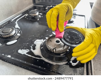 woman cleaning  sponge rag with white foam and detergent washing kitchen gas stove. House cleaning concept - Powered by Shutterstock