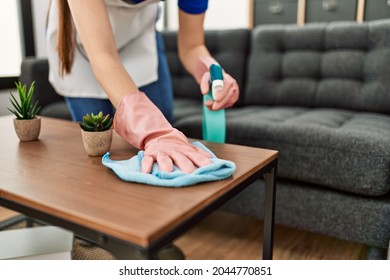 Woman cleaning table using rag and diffuser at home. - Shutterstock ID 2044770851