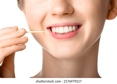 Woman cleaning teeth with bamboo toothpick on white background, closeup