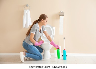 Woman Cleaning Toilet Bowl In Bathroom