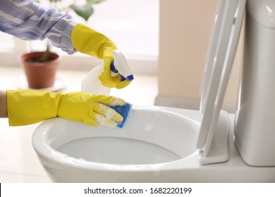 Woman Cleaning Toilet Bowl In Bathroom