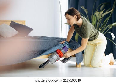 Woman Cleaning Under The Bed With Wireless Vacuum Cleaner