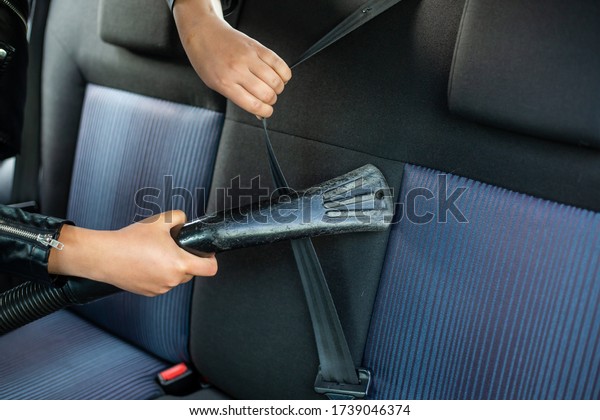Woman cleaning, vacuuming interior of\
the car by vacuum cleaner, transport\
concept