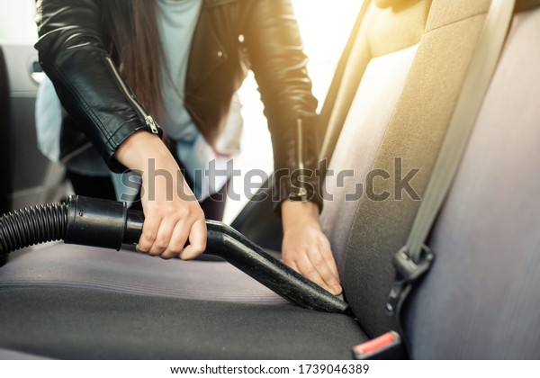 Woman cleaning, vacuuming interior of\
the car by vacuum cleaner, transport\
concept