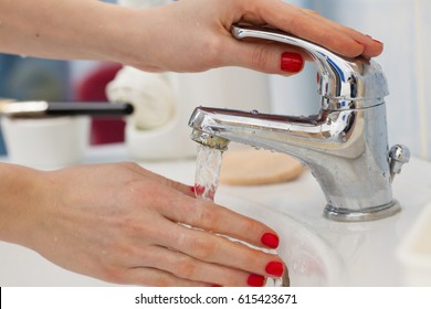 Woman Cleaning Washing Hands Under Flowing Tap Water In The Bathroom. Female Hands With Red Nails Manicure. Hygiene, Skin Treatment Concept.