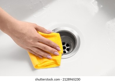 Woman cleaning white sink with wipe, closeup