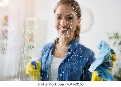Woman cleaning window with special cleaner